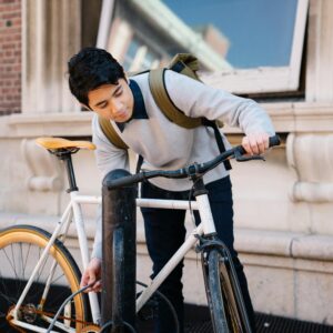 Young man securing his bicycle on a city street, showcasing urban lifestyle and transportation.