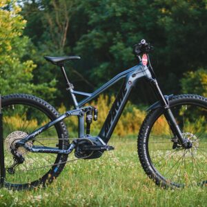 Close-up of a modern mountain bike with gear in a grass field, perfect for adventure and sports enthusiasts.