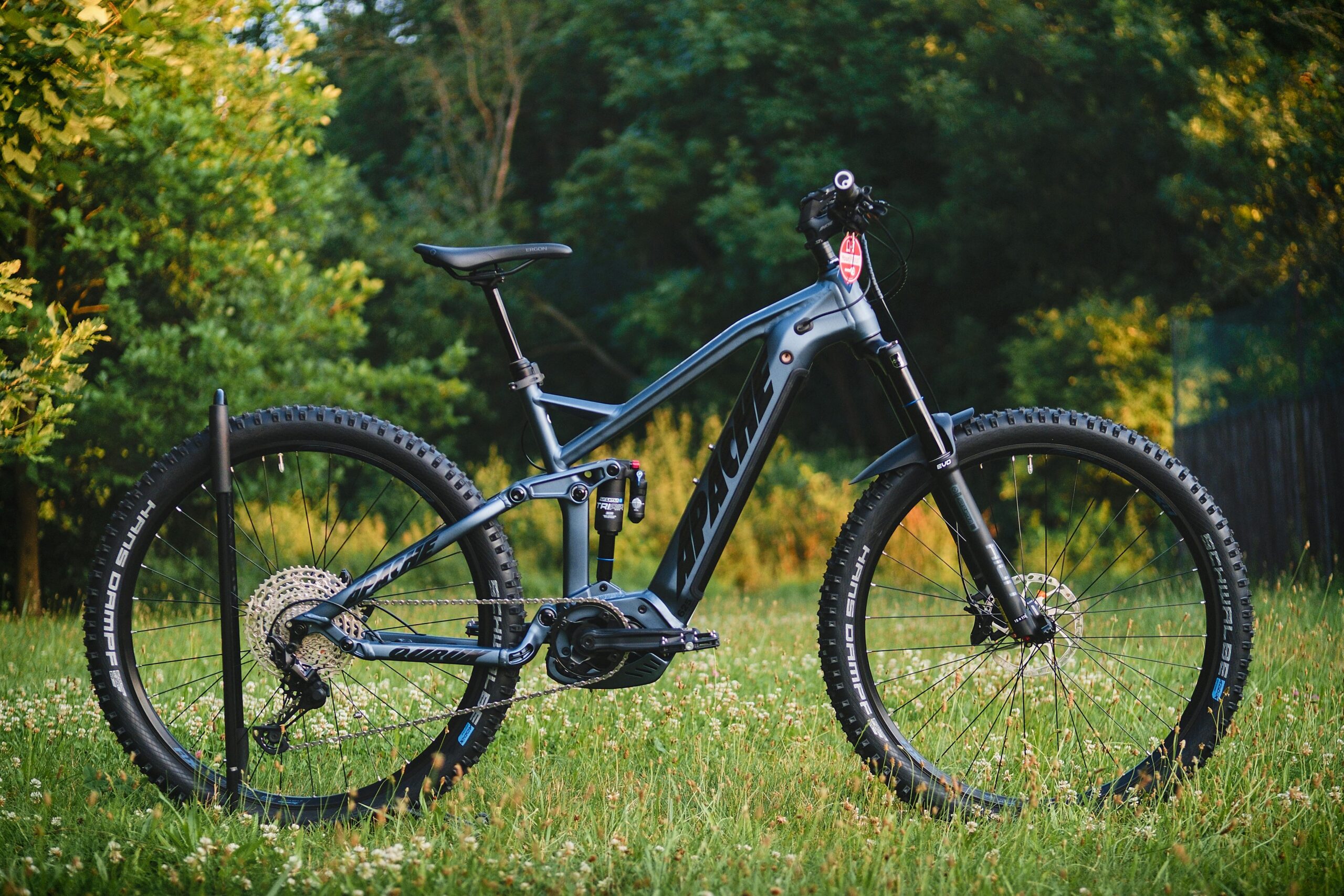 Close-up of a modern mountain bike with gear in a grass field, perfect for adventure and sports enthusiasts.